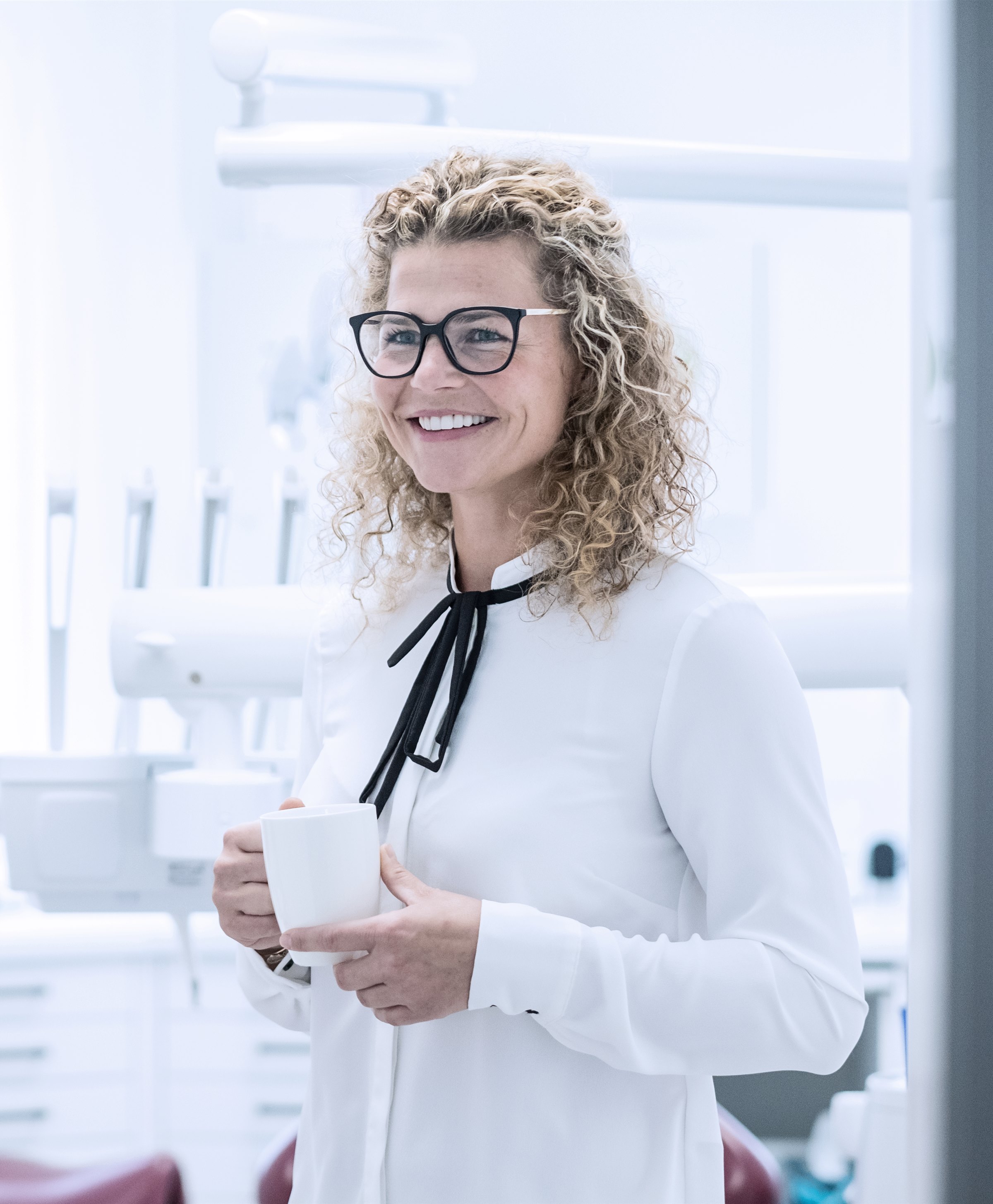 Zahnärztin Julia Richter mit einer Kaffeetasse im Behandlungszimmer